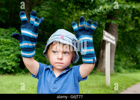 Kleiner Junge mit übergroßen Winterhandschuhen, portrait Stockfoto