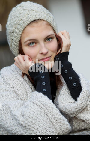 Junge Frau trägt eine Strickjacke und eine Wollmütze Stockfoto