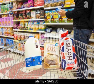 Mann mit Milch, Brot und Haferbrei im Einkaufswagen im Tesco Supermarkt. UK. Steigende Lebensmittelpreise... Stockfoto