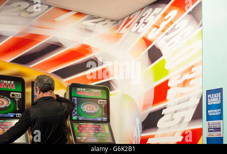 Reifer Mann mit Wetten zu festen Quoten Maschine in Buchmacher. England, UK. Stockfoto