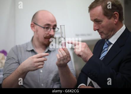 Taoiseach Enda Kenny blickt auf den Wissenschaftler Conor Courtney führt ein DNA-Extraktionsexperiment, bevor er das Programm von vier neuen Ausstellungen für 2014 in der Science Gallery am Trinity College gestartet. Stockfoto