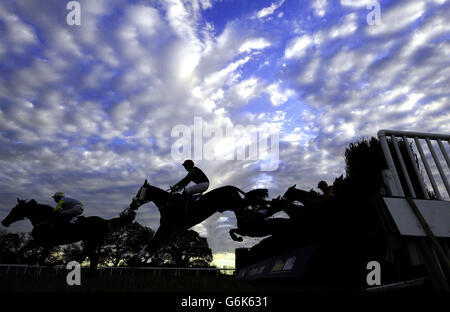 Winteruntergang über der Wetherby-Rennstrecke, während Läufer beim William Hill Yorkshire Winter Festival während des Countryside Day auf der Wetherby Racecourse, Wetherby, einen der Zäune springen. Stockfoto