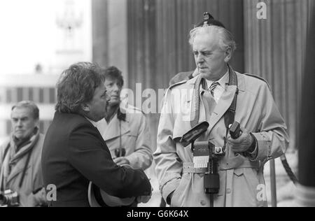 Der Schauspieler George Cole spielt den anhängigen Fotografen bei einer Hochzeit der Gesellschaft während der Dreharbeiten auf den Stufen der St Paul's Cathedral in London für einen weiteren Olympus-Fernsehfilm. Stockfoto