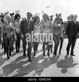 Hugh Hefner, der Chef des Playboy, der von einigen seiner Hasen empfangen wurde, als er aus Amerika am Flughafen London ankam. Hefner, der 40-jährige Herausgeber des Playboy Magazine und Präsident von Playboy Club International, ist hier, um an der Eröffnung seines ersten Playboy Clubs in Europa in der Londoner Park Lane teilzunehmen. Fünfzig der hundert Playboy Club Bunnies in Kostüm begrüßten ihn am Flughafen. Stockfoto