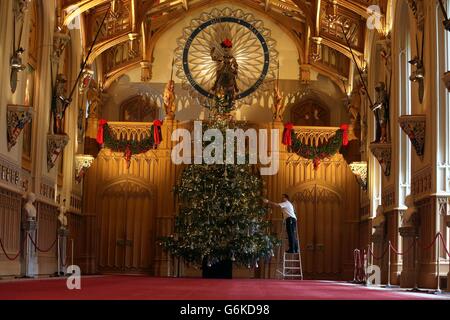 David Westwood, der Konservator der Royal Collection, verleiht einem sechs Meter langen Nordman Fir-Weihnachtsbaum in der St. George's Hall, die Teil der Weihnachtsausstellung im Windsor Castle, Berkshire, ist, den letzten Schliff. Stockfoto