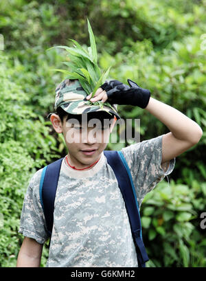 Es ist ein Foto von einen kleinen Jungen Kleid wie ein Soldat. Er ist Tarnung im Wald tut. Stockfoto