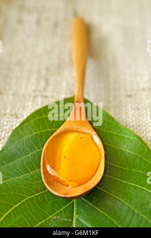 Honig in einem Holzlöffel auf Blatt Stockfoto