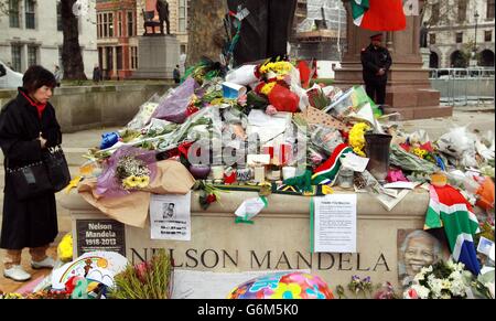 Blumen und Ehrungen für den ehemaligen südafrikanischen Präsidenten an der Nelson-Mandela-Statue auf dem Parliament Square in London. Stockfoto