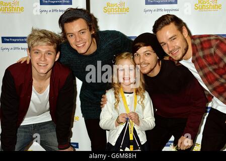 Vier Mitglieder der Boyband One Direction (von links nach rechts) Niall Horan, Harry Styles, Louis Tomlinson und Liam Payne mit Fan Livvie Ellis aus Hertfordshire, bei der Kinderhilfe Rays of Sunshine mit dem Bandfilm This is US im Cineworld Wembley in London, Als kranke Kinder bekommen die Chance, ihre Helden zu treffen und Tickets für ihre Konzerte im nächsten Jahr zu gewinnen. Stockfoto