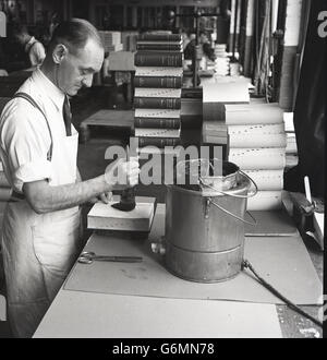 1950er-Jahren, historische, traditionelle maßgeschneiderte Buch binden, zeigt Bild ein männlichen Arbeitnehmers mit Pinsel und Topf mit Kleber, um das Cover eines Buches zu binden. Stockfoto