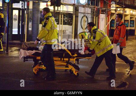 Sanitäter kümmern sich um eine verletzte Person am Schauplatz des Apollo Theaters in der Shaftesbury Avenue, im Zentrum von London, da eine Rettungsaktion im Gange ist, nachdem ein Teil eines Balkons während einer Aufführung eingestürzt ist und Menschen darin einfangen wird, so Augenzeugen. Stockfoto