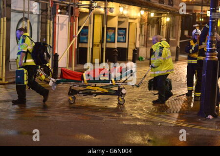 Sanitäter kümmern sich um eine verletzte Person am Schauplatz des Apollo Theaters in der Shaftesbury Avenue, im Zentrum von London, da eine Rettungsaktion im Gange ist, nachdem ein Teil eines Balkons während einer Aufführung eingestürzt ist und Menschen darin einfangen wird, so Augenzeugen. Stockfoto