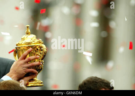 Die Webb Ellis Trophäe wird hoch gehalten, während Englands Rugby-Spieler, die die Weltmeisterschaft gewinnen, durch den Trafalgar Square in London ziehen, während Tausende von Fans die Straßen säumten, um ihre Helden anzufeuern. Kapitän Martin Johnson, Star-Spieler Jonny Wilkinson und der Rest der Mannschaft nahmen an der Sweet Chariot Siegesparade Teil, die ihr Hotel in drei offenen Bussen verließ. Bis zu einer halben Million Menschen verwandelten das Zentrum Londons in ein zwei Meilen langes Gedränge, als die Darstellungen von Swing Low Sweet Chariot ausbrachen. Stockfoto