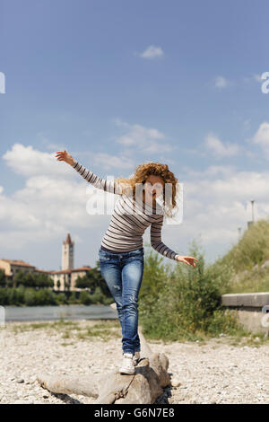 Italien, Verona, Frau balancieren auf Totholz im riverside Stockfoto