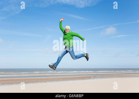 Begeisterte reifer Mann springen am Strand Stockfoto