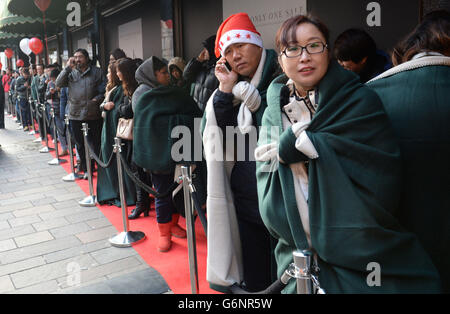 Käufer warten vor Harrods auf den Beginn der Verkäufe am zweiten Weihnachtsfeiertag in Knightsbridge, London. Stockfoto