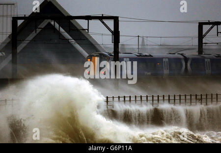 Ein Zug fährt durch die Küste bei Saltcoats in Schottland, da Großbritannien auf das Schlimmste vorbereitet ist, da eine Kombination aus hohen Gezeiten, starken Regenfällen und starken Winden erwartet wird, dass sie Teile des Landes noch schwerer überfluten. Stockfoto