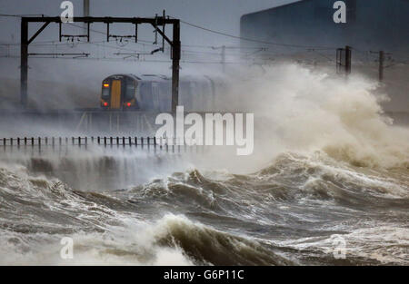 Ein Zug fährt durch die Küste bei Saltcoats in Schottland, da Großbritannien auf das Schlimmste vorbereitet ist, da eine Kombination aus hohen Gezeiten, starken Regenfällen und starken Winden erwartet wird, dass sie Teile des Landes noch schwerer überfluten. Stockfoto