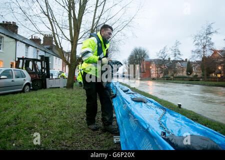 Mitarbeiter der Umweltbehörde legen Sandsäcke auf die Flussschutzbarrieren neben der Themse auf Osney Island in Oxford. Stockfoto