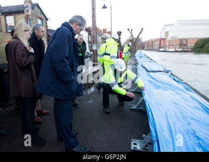 Umweltminister Owen Paterson (Mitte) beobachtet bei einem Besuch auf Osney Island in Oxford, wie Mitarbeiter des Umweltbundesamtes die Flussabwehr überprüfen, da Großbritannien weiterhin von weiteren Überschwemmungen bedroht ist, da der Süden des Landes weiterhin von Regen heimgesucht wird und Gezeitenfluten die Küste überschwemmen. Stockfoto