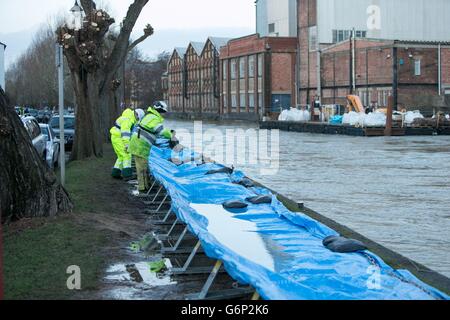 Mitarbeiter der Umweltbehörde kontrollieren die Flussschutzbarrieren auf Osney Island in Oxford, da Großbritannien weiterhin von Überschwemmungen bedroht ist, da der Süden des Landes weiterhin von Regen heimgesucht wird und Gezeitenwellen die Küste überschwemmen. Stockfoto