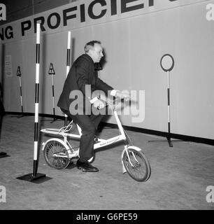 Zurück zu zwei Whells, World Cahmpion Rennfahrer, John Surtees führt nach der Eröffnung der Internationalen Rad- und Motorradrennausstellung am earls Court einen Radlauf durch einen Testkurs. Er erhielt eine 70%-Marke und versagte den Test. Vor der Aufnahme des Motorrakings war Surtees Weltmeister im Motorradfahrer Stockfoto