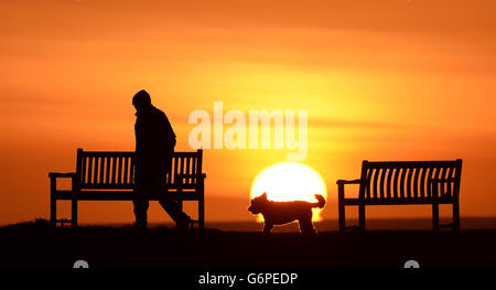 Winterwetter 24. Januar. Ein Mann geht mit seinem Hund, während die Sonne in Tynemouth aufgeht. Stockfoto