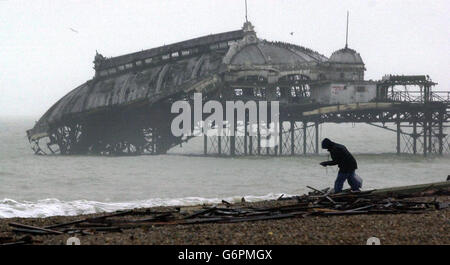 Ein Mann, der am Strand von Brighton entlang durch das Wrack ging, das vom historischen West Pier der Stadt an Land gespült wurde, von dem er am 30. Dezember 2002 ins Meer einstürzte. Pläne zur Wiederherstellung Brighton verfallenen West Pier brach heute, Mittwoch, 28. Januar 2004, mit dem Rückzug von Millionen Pfund Lotterie-Finanzierung. Bis zu 19 Millionen wurden vom Heritage Lottery Fund für die Gesamtkosten von 40 Millionen zugesagt, die für die Wiederherstellung des 135 Jahre alten viktorianischen Wahrzeichen erforderlich waren. Stockfoto