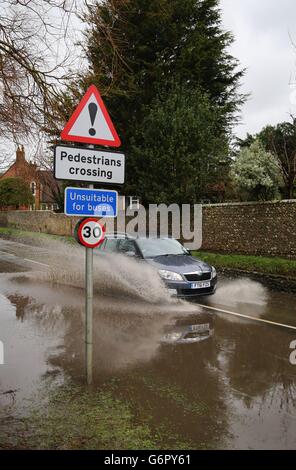 Ein Auto fährt durch eine überflutete Straße in Alfriston, East Sussex, während mehr heftiger Regen über das Land fegt. Stockfoto