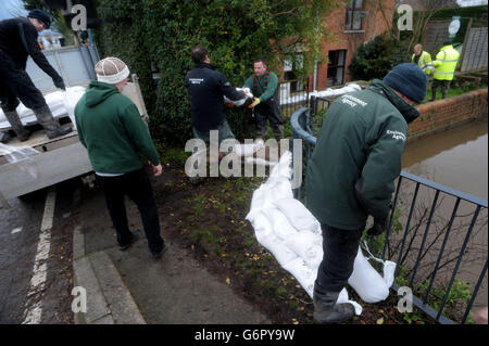 Mitarbeiter der Umweltbehörde tragen einen Sandsack am Fluss Parrett in Burrowbridge, Somerset, da die Überschwemmungen auf den Ebenen andauern. Stockfoto