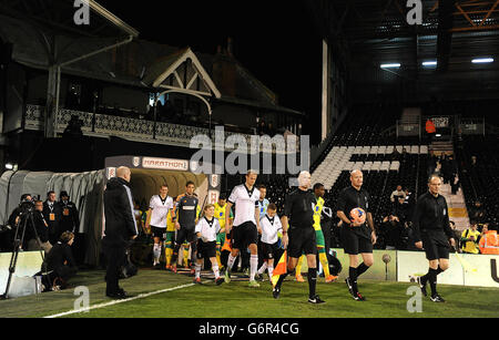 Fußball - FA Cup - Dritte Runde - Replay - Fulham gegen Norwich City - Craven Cottage. Spielbeamte führen Spieler beider Teams vor dem Anpfiff auf das Spielfeld Stockfoto