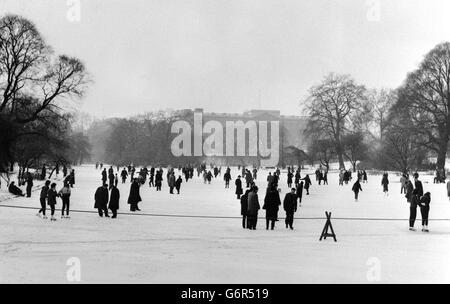 Im Schatten des Buckingham Palace fahren Skater und Slider auf das Eis des gefrorenen St. James's Park Lake, London. Stockfoto