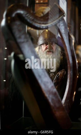 Ian Barber von der Finagal Living History Society blickt auf die mittelalterliche Brian Boru Harp bei der Einführung des Brian Boru-Jahresprogramms für 2014 am Trinity College in Dublin. Stockfoto