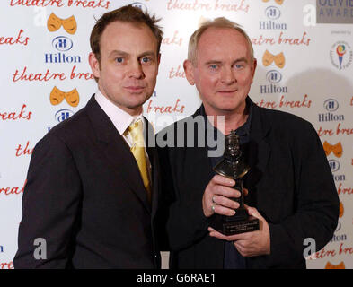 Der Regisseur des Eugene O'Neill-Spiels Howard Davies (R) mit seiner Auszeichnung für die beste Wiederbelebung für Mourning Becomes Electra, die ihm von Jason Donavan bei den Laurence Olivier Awards 2004 im Londoner Hilton, Park Lane, im Zentrum von London, überreicht wurde. Stockfoto