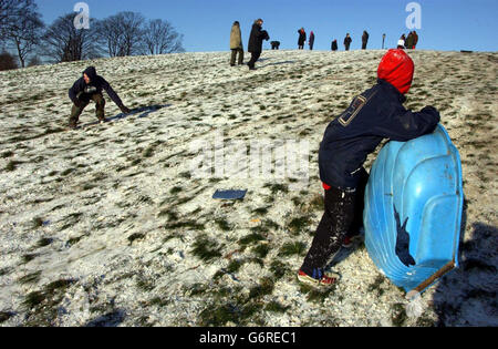 Kinder, die aufgrund der winterlichen Bedingungen einen guten Schultag erhalten haben, ziehen ihre Winterwölpel an und rodeln auf ihren Schichtschleifschlitten den Primrose Hill, London, hinunter, während die Arktis im ganzen Land weiter bläst. Die Kälte, die Großbritannien überschwemmte, hat Straßen-, Schienen- und Flugreisende gestört, obwohl man hoffte, dass das schlimmste Wetter nach dem gestrigen Schnee vorbei war. Stockfoto