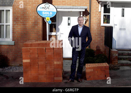 Russell Quirk, Gründer der Low Cost Online-Immobilienagentur eMoov.co.uk, vergleicht die verschiedenen kommissionen, die von britischen Immobilienmaklern im Vergleich zu eMoov.co.uk verdient wurden, die durch Ziegelstapel außerhalb einer Immobilie in Brentwood, Essex, repräsentiert werden. Stockfoto