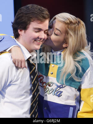 Rita Ora mit Sean Bommer, 17, dem Schüler der St Mungo Academy, als sie ihn während der BBC Radio 1 Breakfast Show von Nick Grimshaw, die von BBC Scotland in Glasgow ausgestrahlt wurde, auf die Wange küsst. Stockfoto