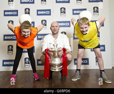 Der Weltmeister im Freistil Billy Fincham hält den FA Cup mit den Schülern Erin Clitheroe und Alex Mullen beim Start der Beko Keepy-Uppy Challenge in der Hillsborough Primary School in Sheffield, im Süden von Yorkshire, Als Beko „The Official Home Appliance Partner of the FA Cup“ ermutigt Beko Gemeinden in ganz Großbritannien, aktiv zu werden. Stockfoto