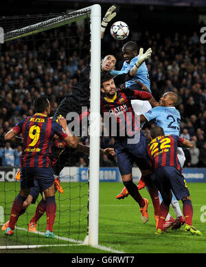 Die Yaya Toure von Manchester City kämpft mit Victor Valdes und Gerard Pique vom FC Barcelona während des UEFA Champions League-Spiels der 16. Runde im Etihad Stadium in Manchester um den Ball. Stockfoto