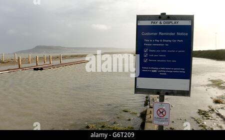 Ein überfluteter Parkplatz an der Portland Beach Road in der Nähe von Weymouth in Dorset, nach hohen Gezeiten und starken Winden, wurde die Straße vorübergehend gesperrt, um Portland vom Festland abzuschneiden. Stockfoto