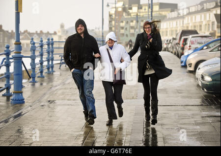Die Menschen kämpfen, um ihren Weg entlang der Esplanade, Porthcawl, Südwales zu machen, da die Region weiterhin von starken Winden und starken Regenfällen geschlagen wird. Stockfoto