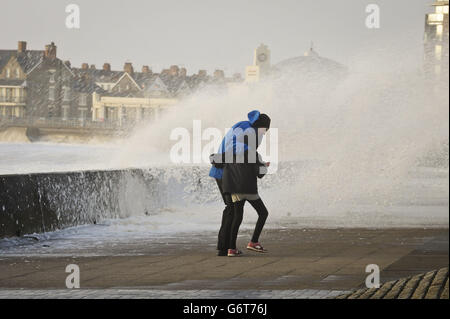 Die Menschen kämpfen, um ihren Weg entlang der Esplanade, Porthcawl, Südwales zu machen, da die Region weiterhin von starken Winden und starken Regenfällen geschlagen wird. Stockfoto