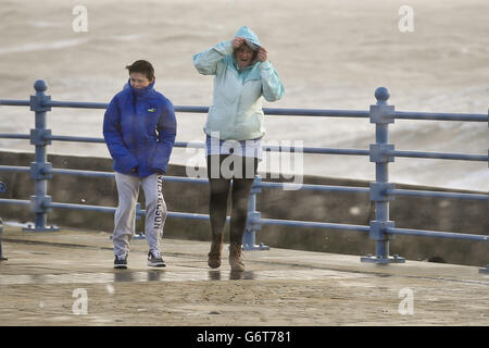 Die Menschen kämpfen, um ihren Weg entlang der Esplanade, Porthcawl, Südwales zu machen, da die Region weiterhin von starken Winden und starken Regenfällen geschlagen wird. Stockfoto
