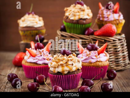 Verschiedene leckere Muffins verziert mit Karamell und frischen Beeren Stockfoto