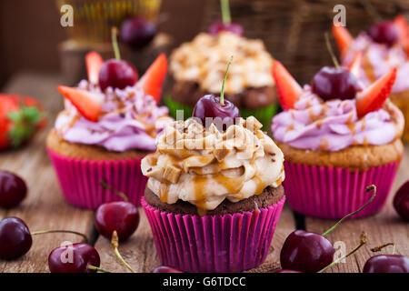 Verschiedene leckere Muffins verziert mit Karamell und frischen Beeren Stockfoto