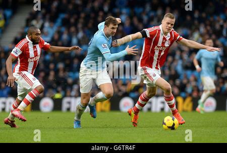 Edin Dzeko von Manchester City kämpft mit Ryan Shawcross von Stoke City (rechts) und Wilson Palacios (links) während des Spiels der Barclays Premier League im Etihad Stadium in Manchester um den Ball. Stockfoto