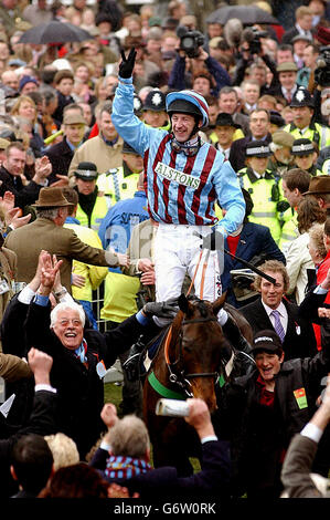 Jim Culloty auf Best Mate und Besitzer Jim Lewis (links unten) feiern ihren dritten Sieg in Folge im Cheltenham Gold Cup Hindernislauf am dritten und letzten Tag des Cheltenham Festival Treffens. Stockfoto