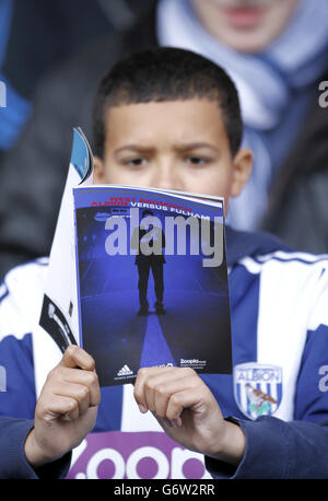 Fußball - Barclays Premier League - West Bromwich Albion gegen Fulham - The Hawthorns. Ein junger Fan von West Bromwich Albion liest das Spieltagsprogramm auf den Tribünen Stockfoto