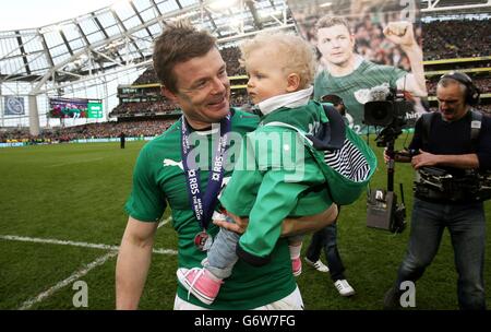 Der irische Brian O'Driscoll trägt seine Tochter Sadie nach seinem letzten Heimspiel beim RBS Six Nations-Spiel im Aviva Stadium, Dublin, Irland, auf dem Spielfeld. Stockfoto