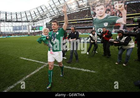 Der irische Brian O'Driscoll trägt seine Tochter Sadie nach seinem letzten Heimspiel beim RBS Six Nations-Spiel im Aviva Stadium, Dublin, Irland, auf dem Spielfeld. Stockfoto